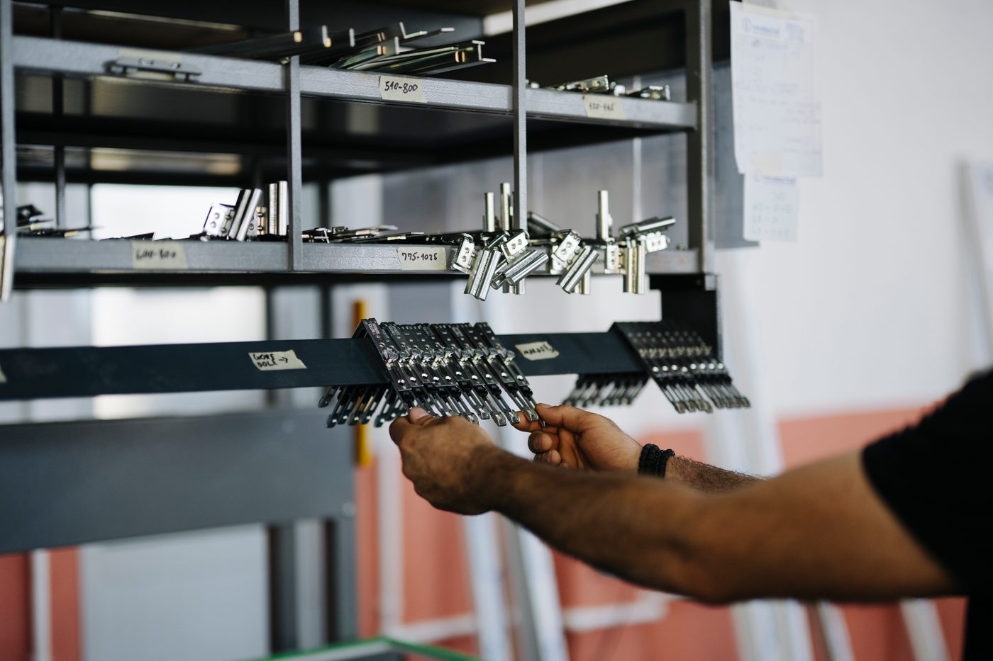 A worker picking hardware from labelled storage racks in a manufacturing facility.